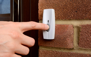 Close-up of someone pressing a button on a doorbell